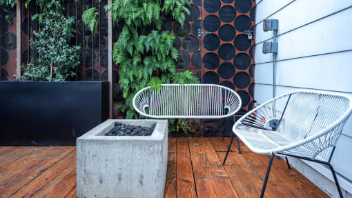a patio with two chairs and a concrete fire pit