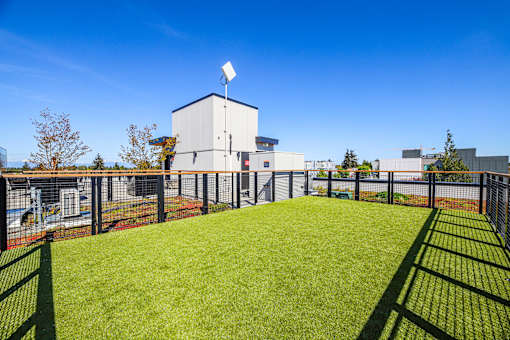 A white building with a solar panel on top is surrounded by a green fence.