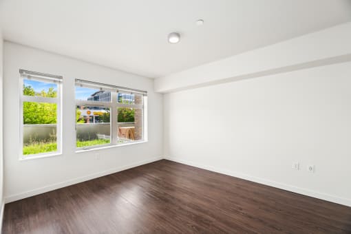 a living room with wood floors and white walls and windows