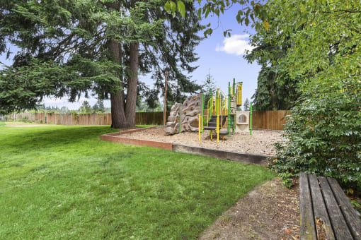 a playground in a backyard with trees and a picnic table