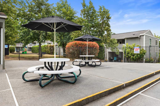 two tables with umbrellas in an empty parking lot