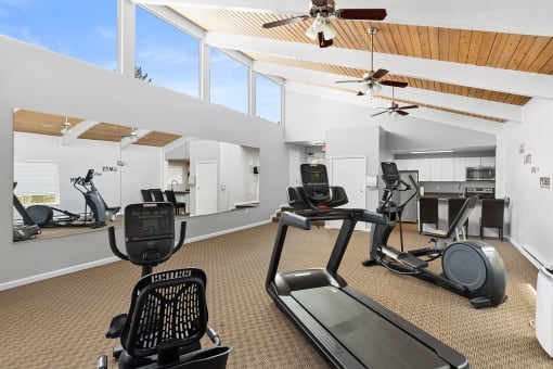 a gym with treadmills and other exercise equipment in a room with windows