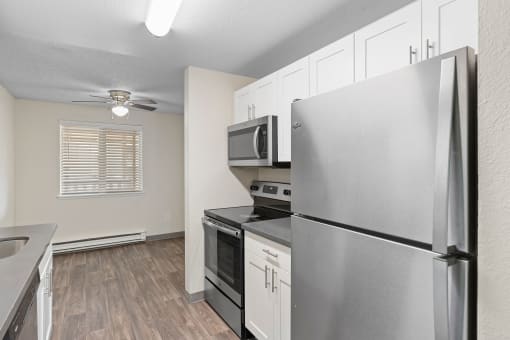 an empty kitchen with stainless steel appliances and a ceiling fan