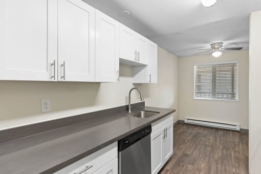 an empty kitchen with white cabinets and a sink