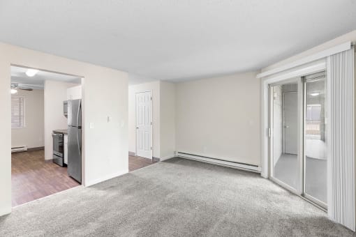 an empty living room with sliding glass doors to a kitchen