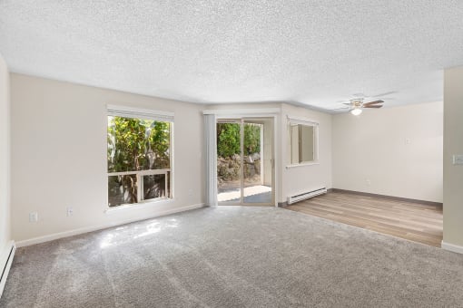 an empty living room with a ceiling fan and a window