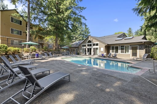 a swimming pool with chairs and a house in the background