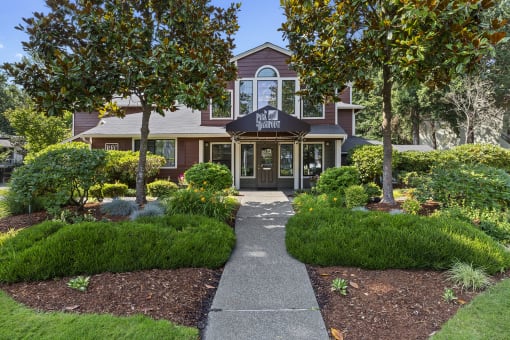 the front of a house with a walkway and trees