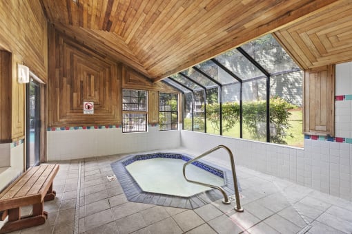 a hot tub in a room with wooden ceilings and windows