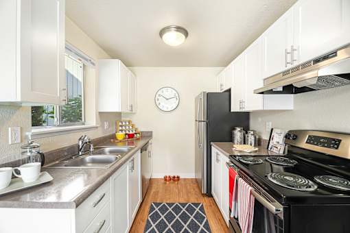 A kitchen with a black stove top oven and a clock on the wall.