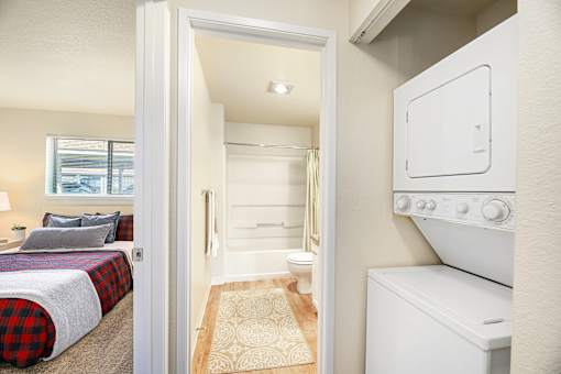 A small bedroom with a bed, a toilet, and a washing machine.