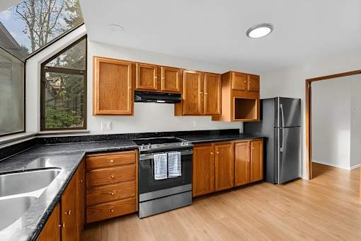 A kitchen with wooden cabinets and black countertops.