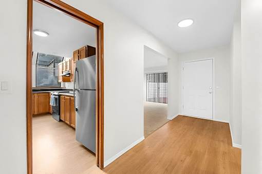 A kitchen with a refrigerator and wooden cabinets is visible through a mirror.
