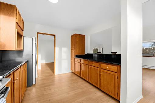 A kitchen with wooden cabinets and black countertops.