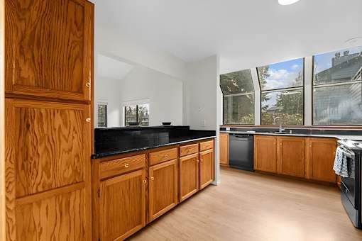 A kitchen with wooden cabinets and black countertops.