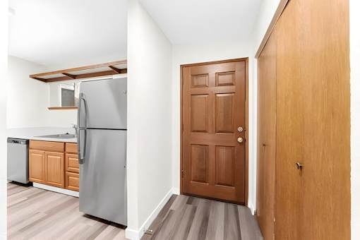 A kitchen with a refrigerator, dishwasher, and wooden cabinets.