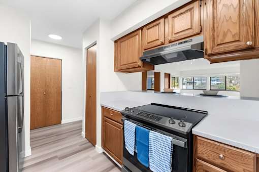 A kitchen with a black stove top oven and wooden cabinets.
