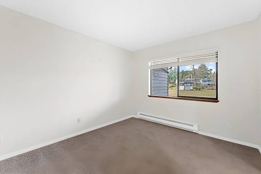 A room with a window showing a view of a house and trees outside.