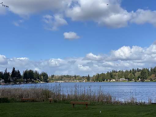 A serene landscape with a bench in the foreground and a body of water in the background.
