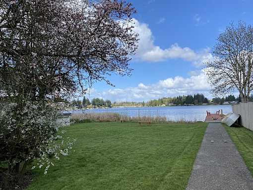 A park with a grassy area, a walking path, and a body of water.