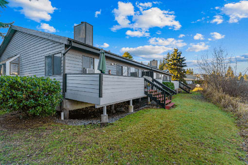 A house with a grey siding and a green lawn.