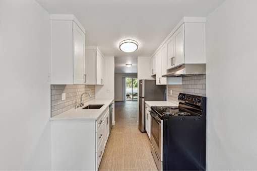 A modern kitchen with white cabinets and a black stove top oven.