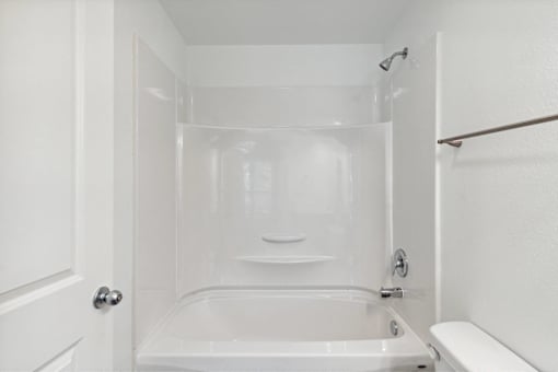 A white bathroom with a tub, toilet, and sink.