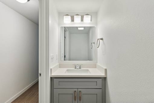 A bathroom with a sink, mirror, and lights.
