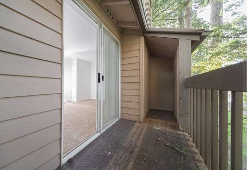 A deck with a sliding glass door leading to a room.