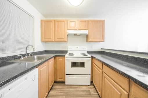 A kitchen with wooden cabinets and a white stove top oven.