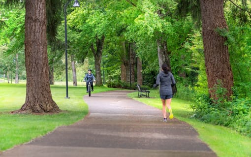 people walking and biking on a path in a park