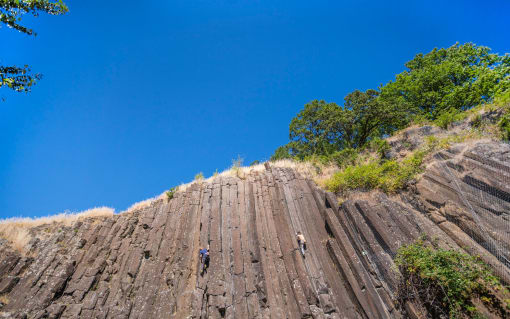 people climbing up a rock face with a blue sky in the background