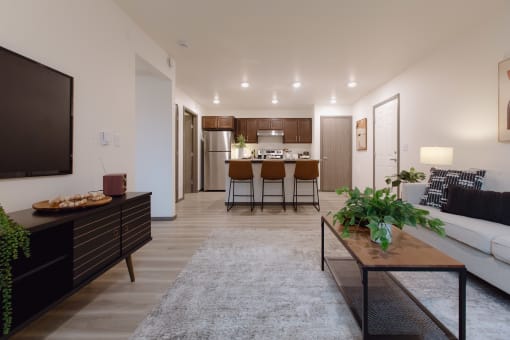 a living room with a couch and a table in front of a kitchen