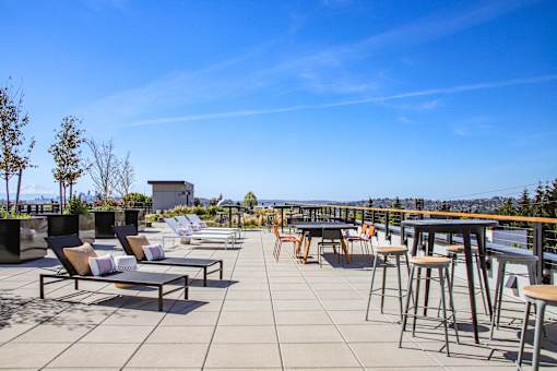 A patio with chairs and tables overlooking a city.