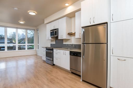 an empty kitchen with stainless steel appliances and white cabinets