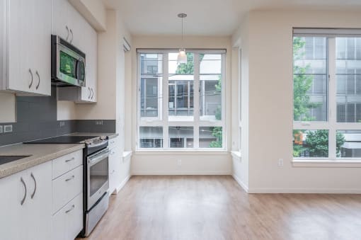 an empty kitchen with white cabinets and a window
