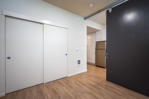 a bedroom with a black door and a kitchen with a refrigerator and