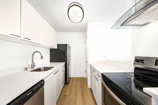 A modern kitchen with white cabinets and black appliances.