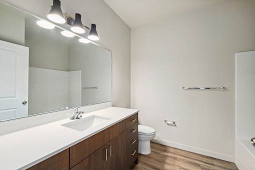 A white sink with a mirror above it and a toilet in the corner.