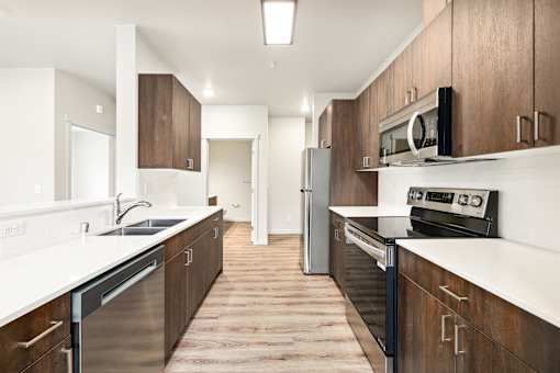 A modern kitchen with dark wood cabinets and stainless steel appliances.