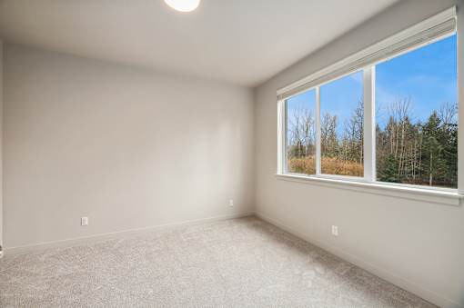 A room with a window showing a view of trees and sky.