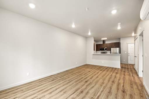 A spacious room with wooden flooring and white walls.