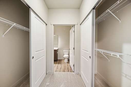 A hallway with white doors and a toilet in the background.