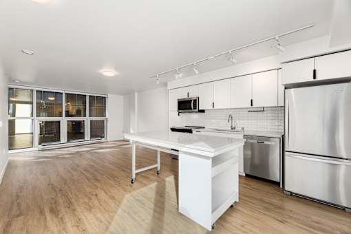 A modern kitchen with a white island and stainless steel appliances.