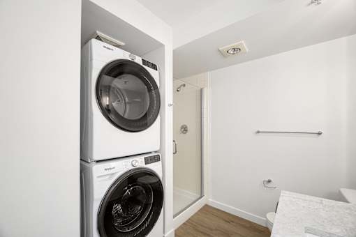 A white washing machine and dryer stacked on top of each other in a small room.