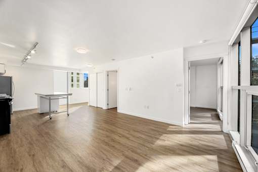 A room with white walls and wooden flooring, furnished with a desk and a cabinet.
