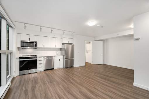 A kitchen with stainless steel appliances and wooden floors.