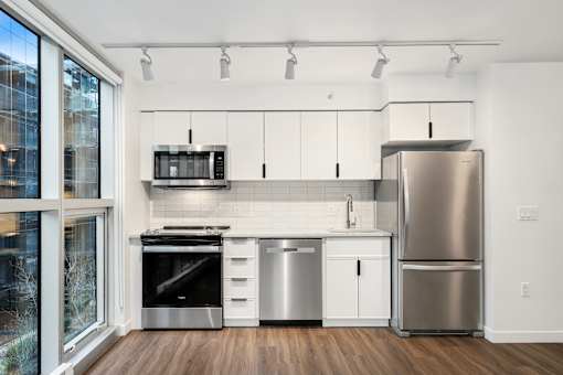 A modern kitchen with stainless steel appliances and white cabinetry.