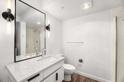 A white bathroom with a sink, toilet, and mirror.