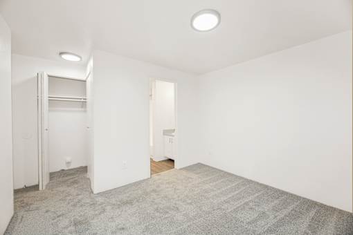 A white room with a grey carpet and a small wooden table.